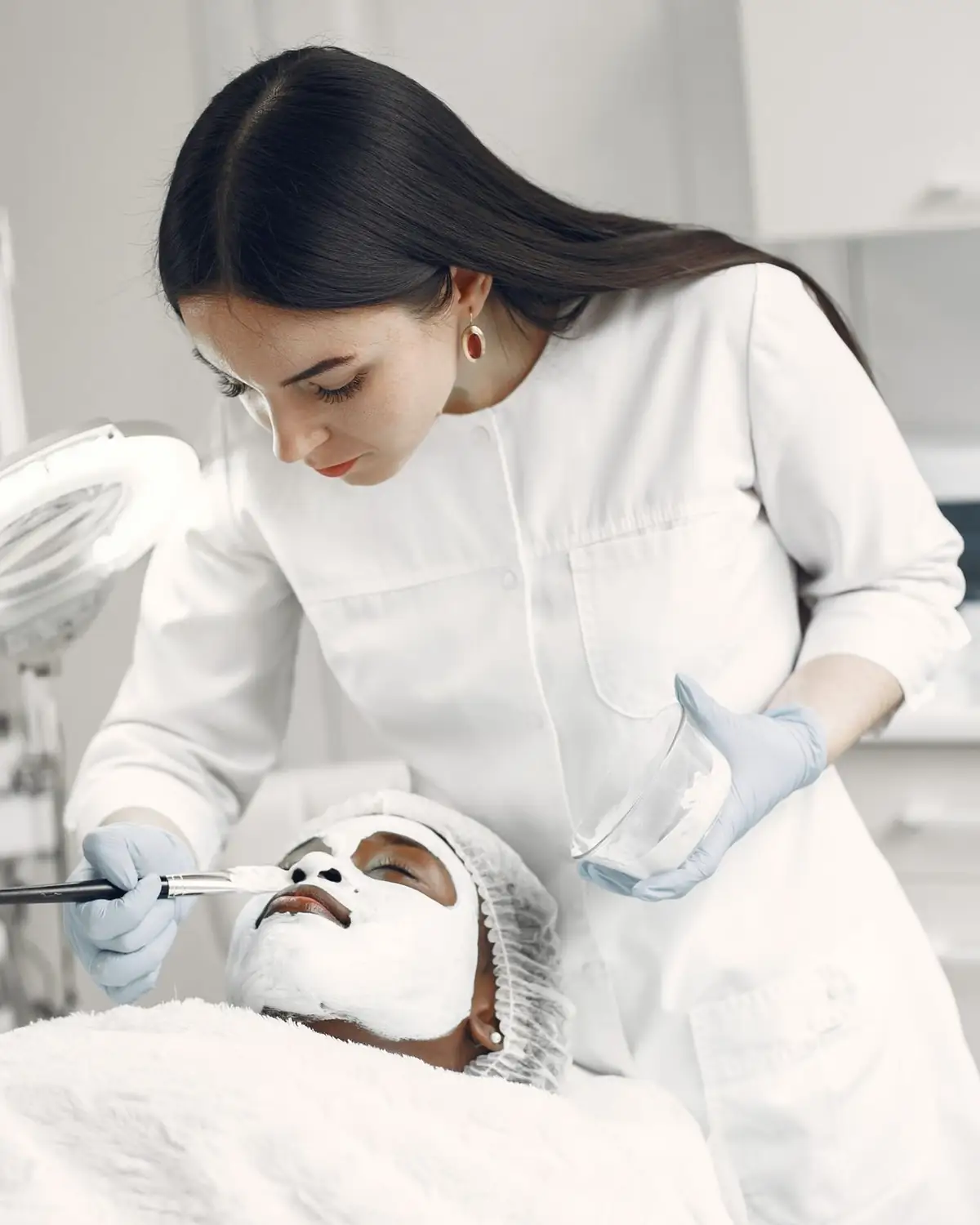 Esthéticienne qui applique un masque sur le visage d’une cliente