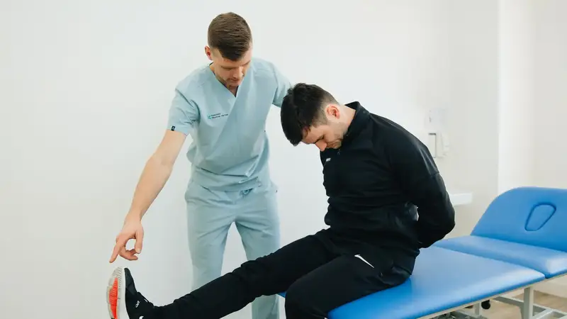 Kinesitherapeut begeleidt een patiënt bij een oefening