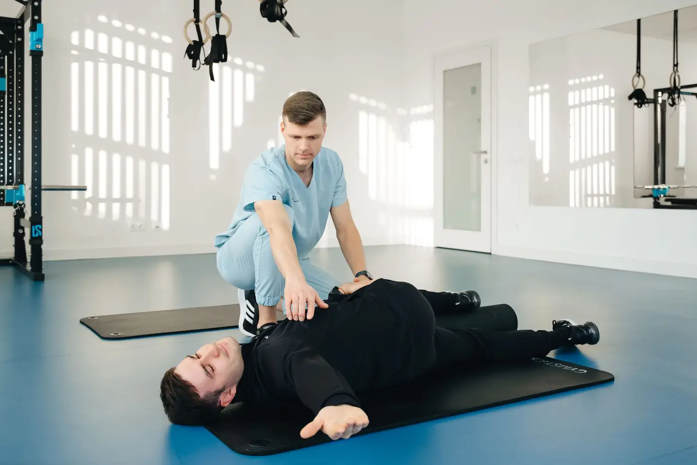 Kinesitherapeut begeleidt een oefening op de mat