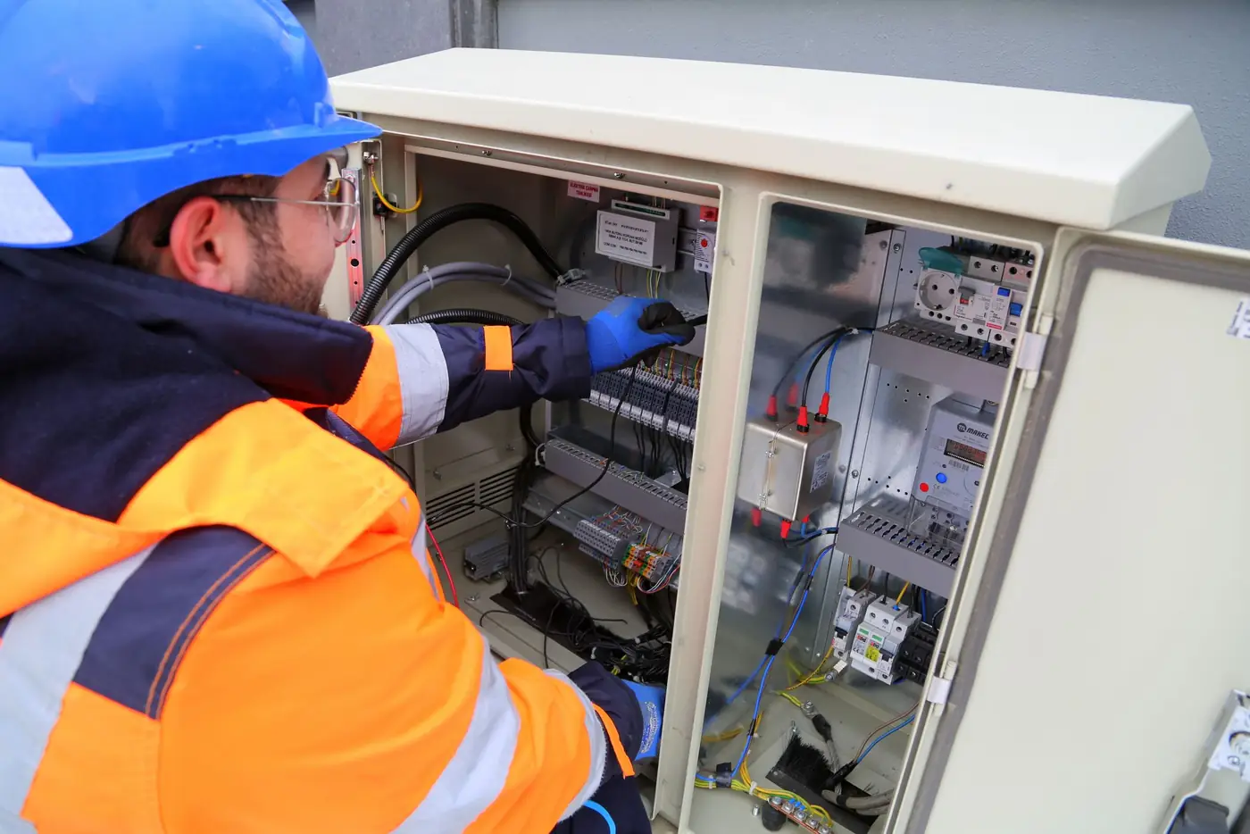 Elektriker mit Helm arbeitet an einem Schaltschrank