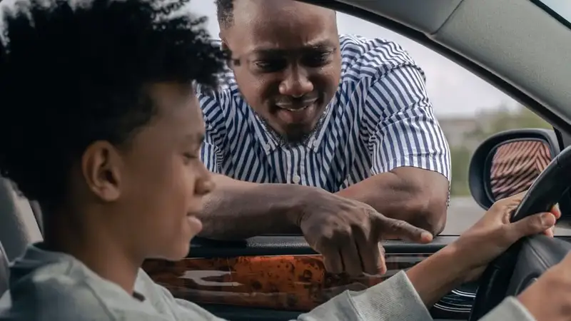 Fahrlehrer erklärt einem jungen Fahrschüler im Auto etwas