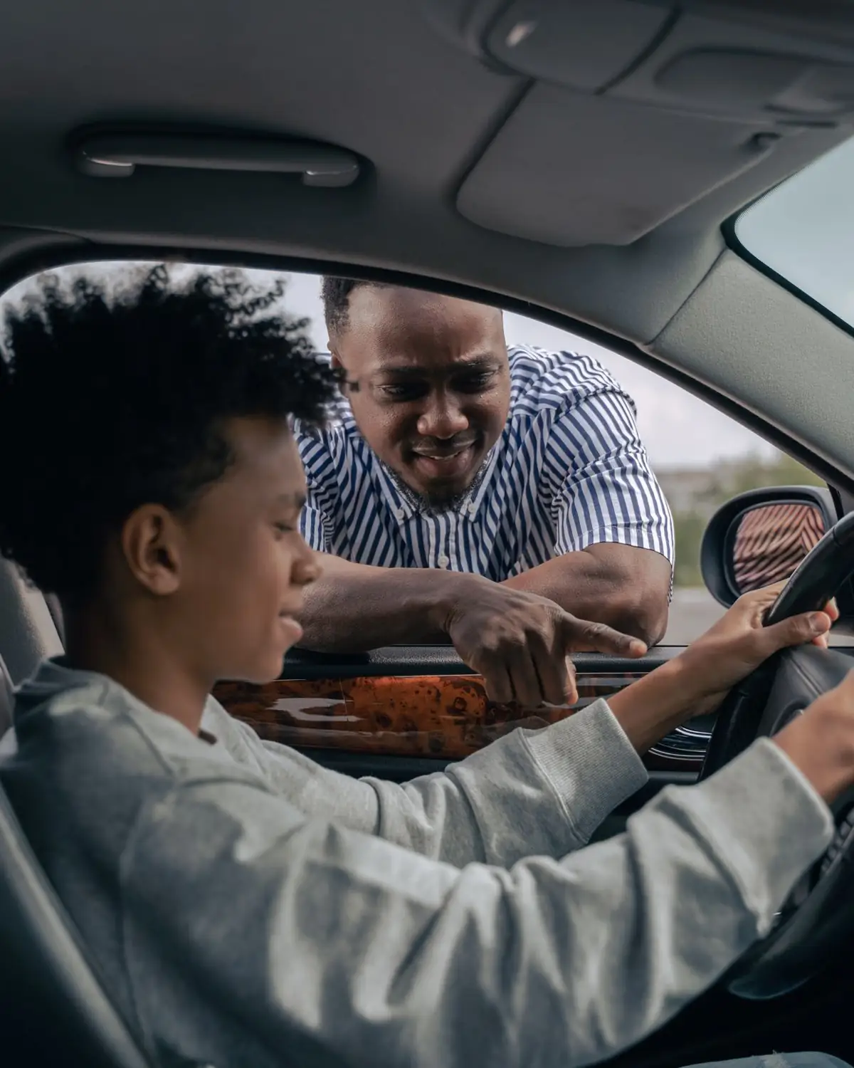 Fahrlehrer erklärt einem jungen Fahrschüler im Auto etwas