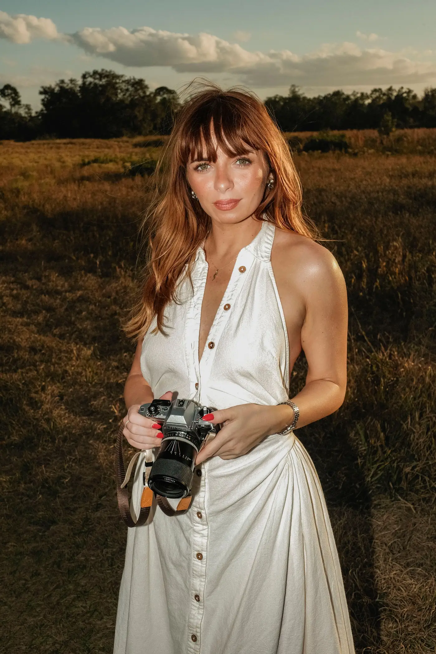 Fotografin im weißen Kleid mit Kamera auf einem Feld