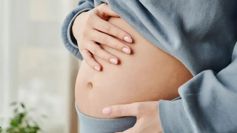 Schwangere Frau hält ihre Hände an den Bauch