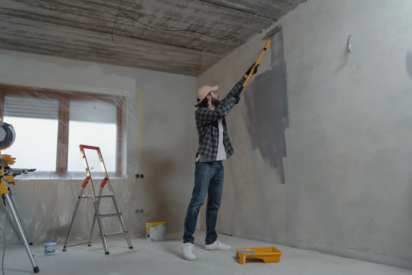 Maler streicht eine Wand mit Teleskoprolle