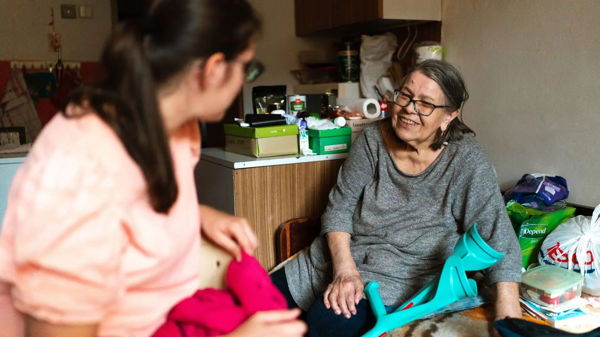 Pflegerin hilft einer Seniorin mit Gehstütze in der Wohnung