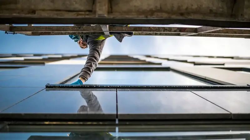Fensterputzer reinigt eine Glasfassade, von unten fotografiert