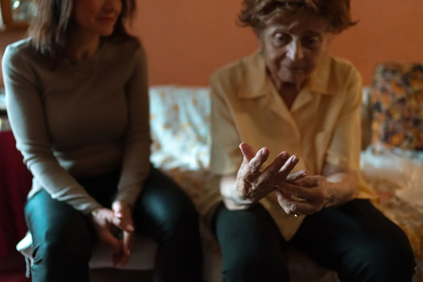 Junge Frau hört einer älteren Dame im Wohnzimmer zu