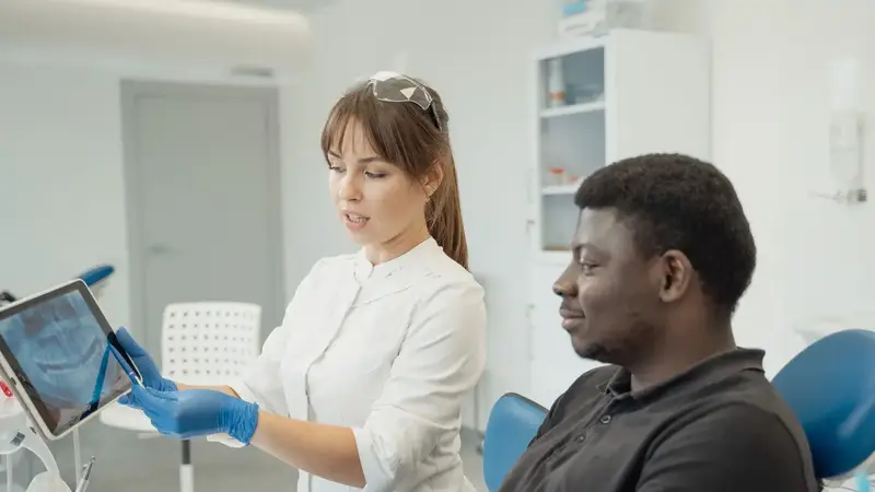 Zahnärztin spricht mit einer Patientin im Behandlungsstuhl