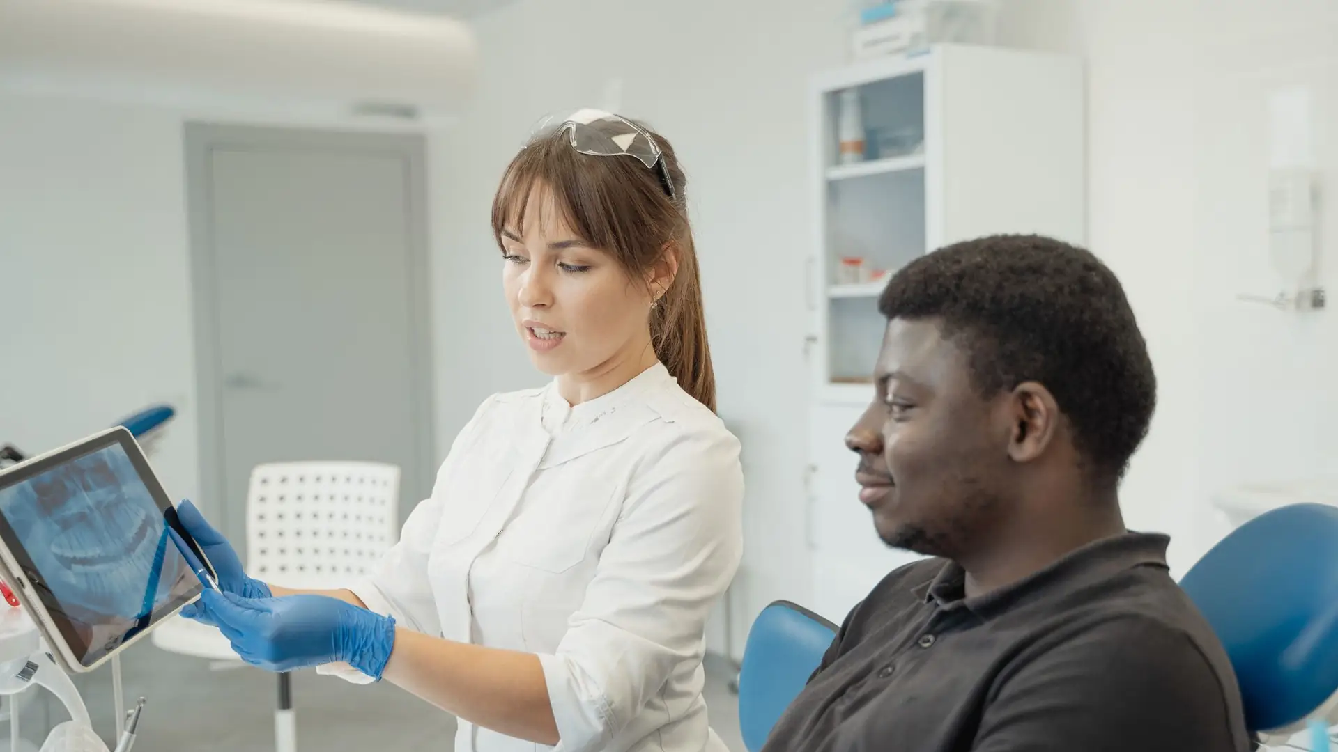 Zahnärztin spricht mit einer Patientin im Behandlungsstuhl