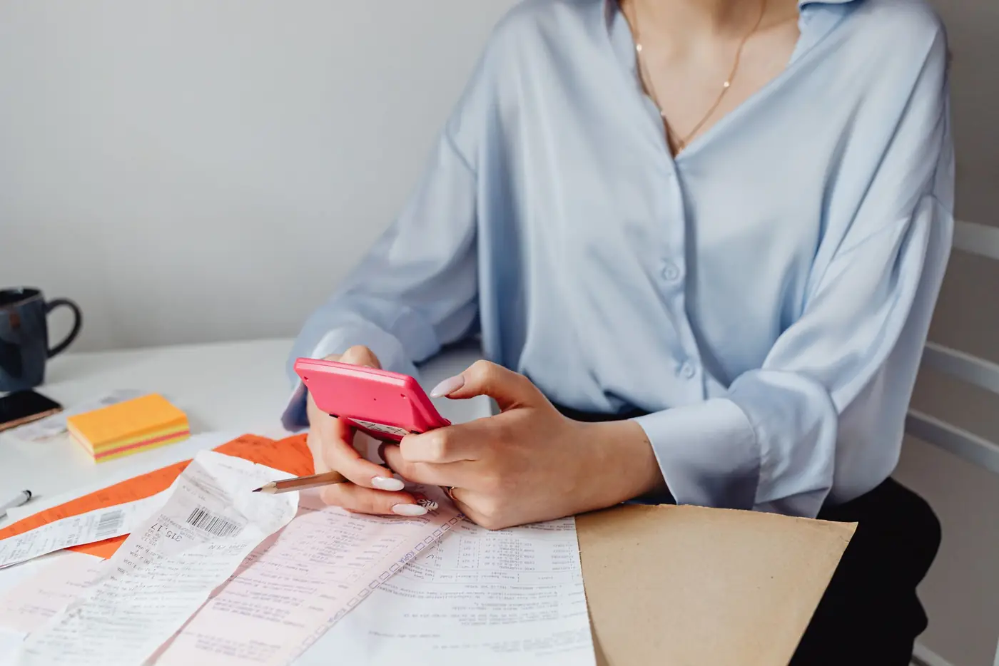 Hands holding a phone over tax paperwork and a calculator