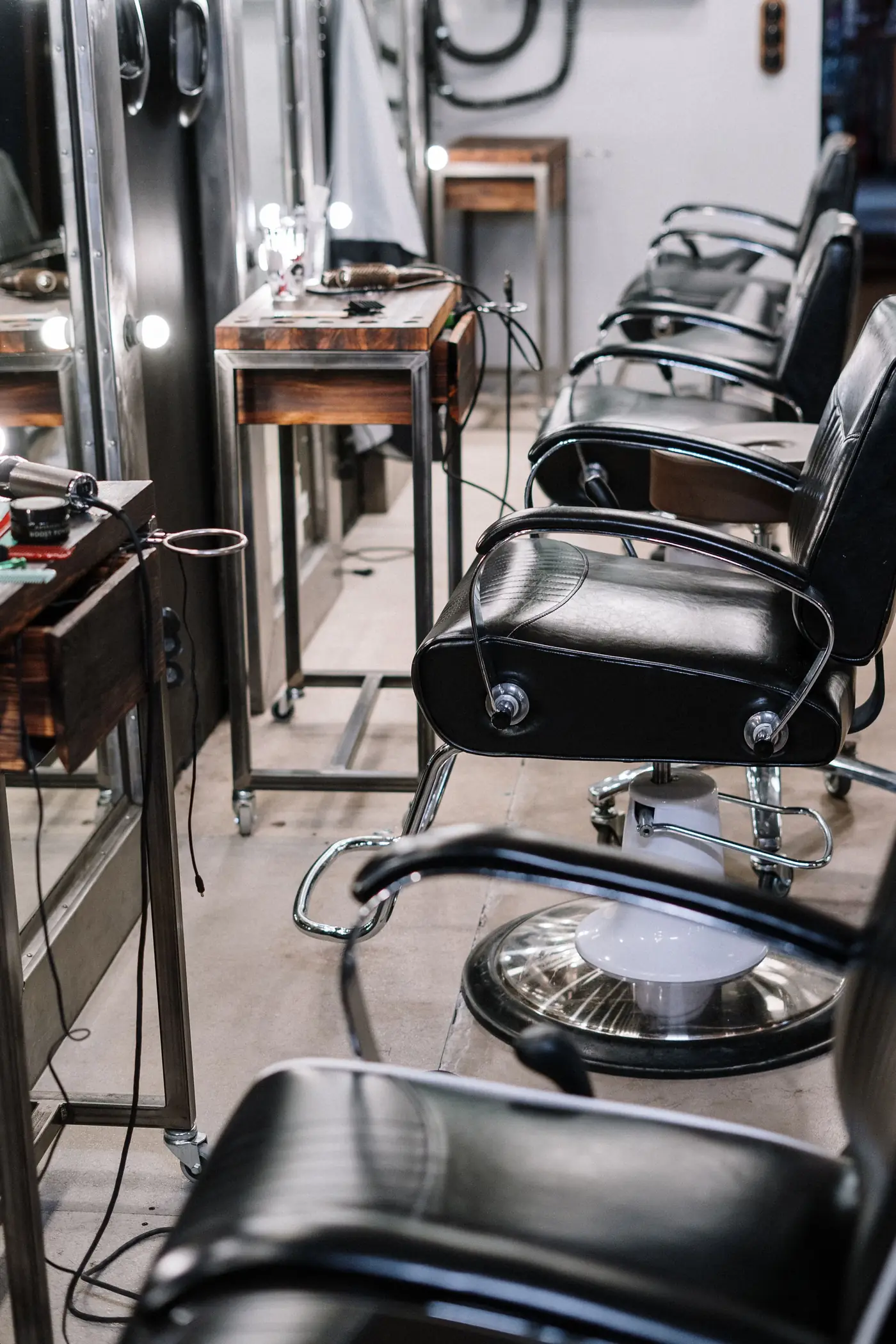 Row of black salon chairs and mirrors
