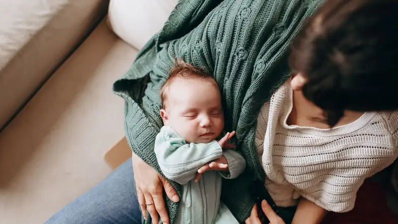 Moeder houdt haar slapende pasgeboren baby vast
