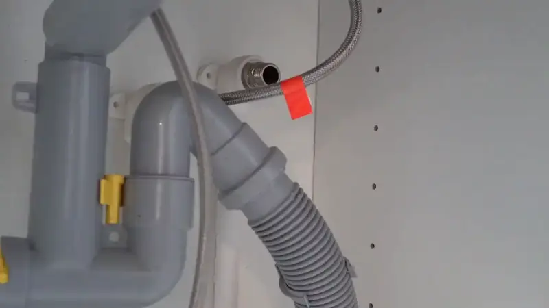 Monteur sluit een afvoer onder een wastafel aan