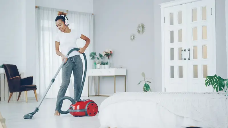 Cleaner hoovering a bright white living room