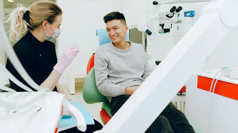 Dentist chatting with a smiling patient in the chair