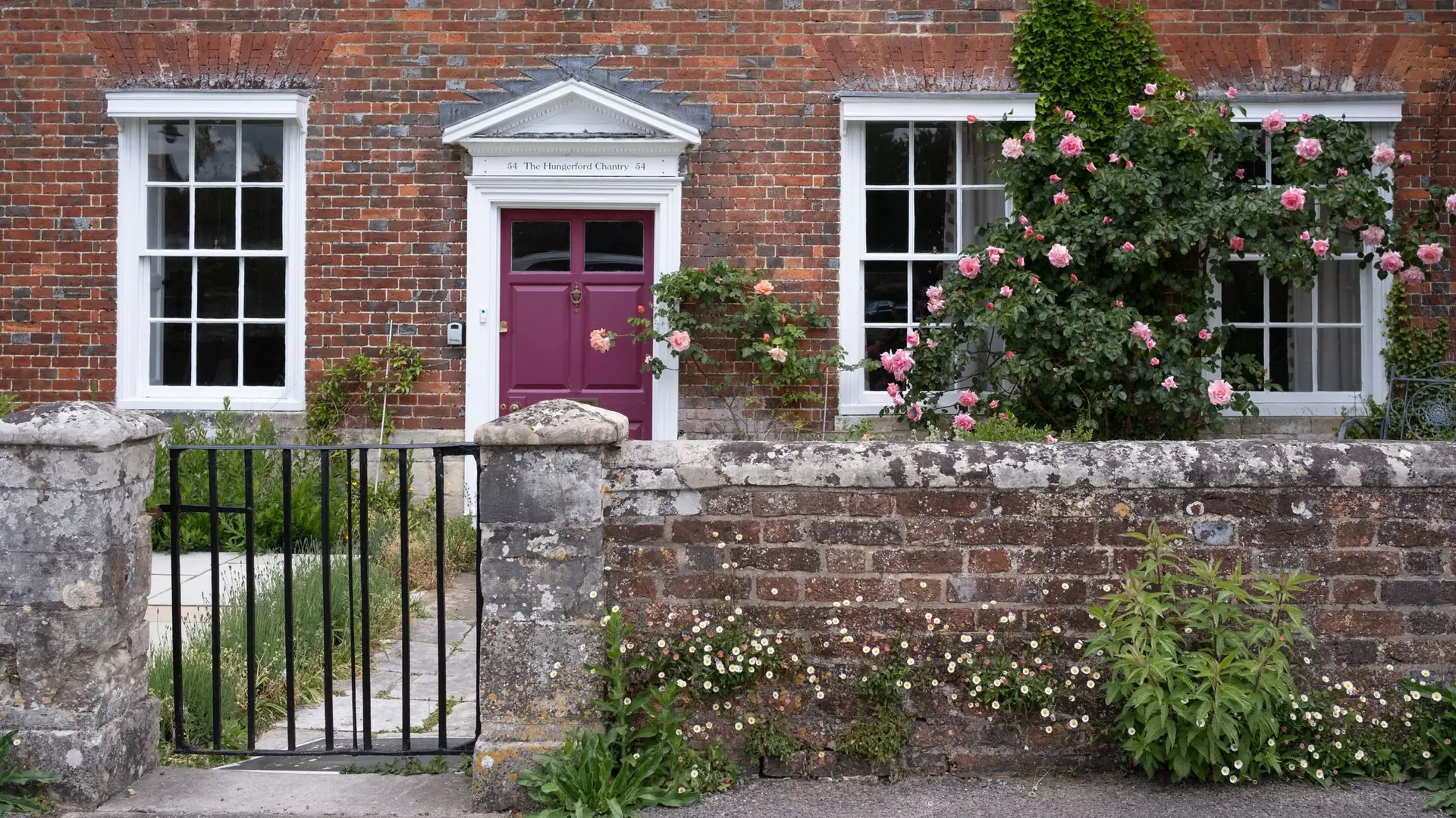 Red brick house with a front garden and stone wall