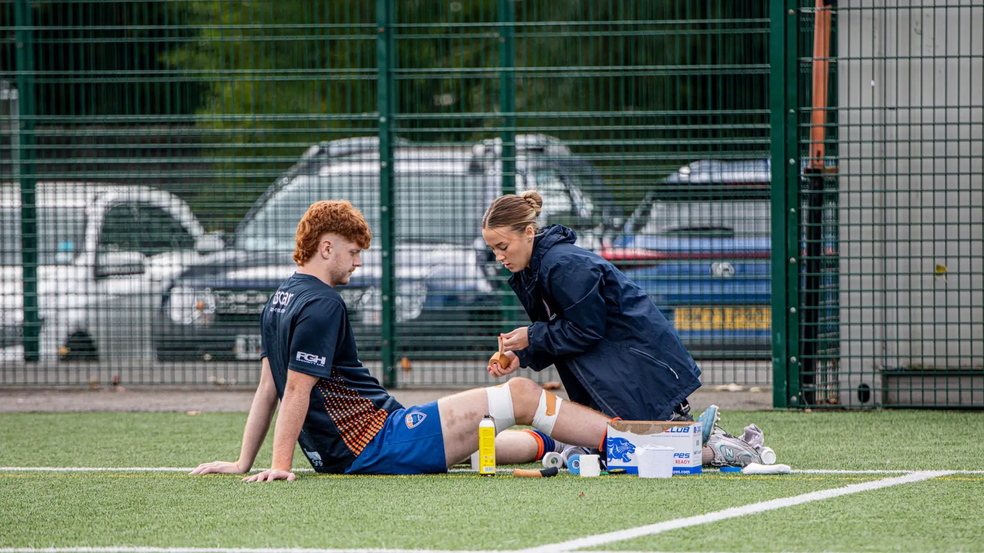 Physio treating a footballer’s leg on an artificial pitch